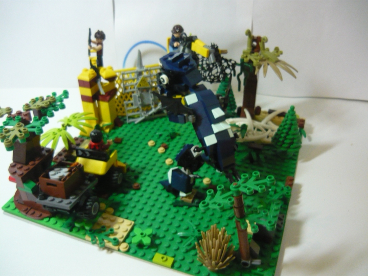 LEGO MOC - Jurassic World - Атака разъяренного динозавра на лагерь охотников.: Общий вид работы. Вы можете рассмотреть всю композицию. Видим, что динозавр ломая деревья пробирается к базе, к которой так же спешит внедорожник. Всё это происходит в джунглях.